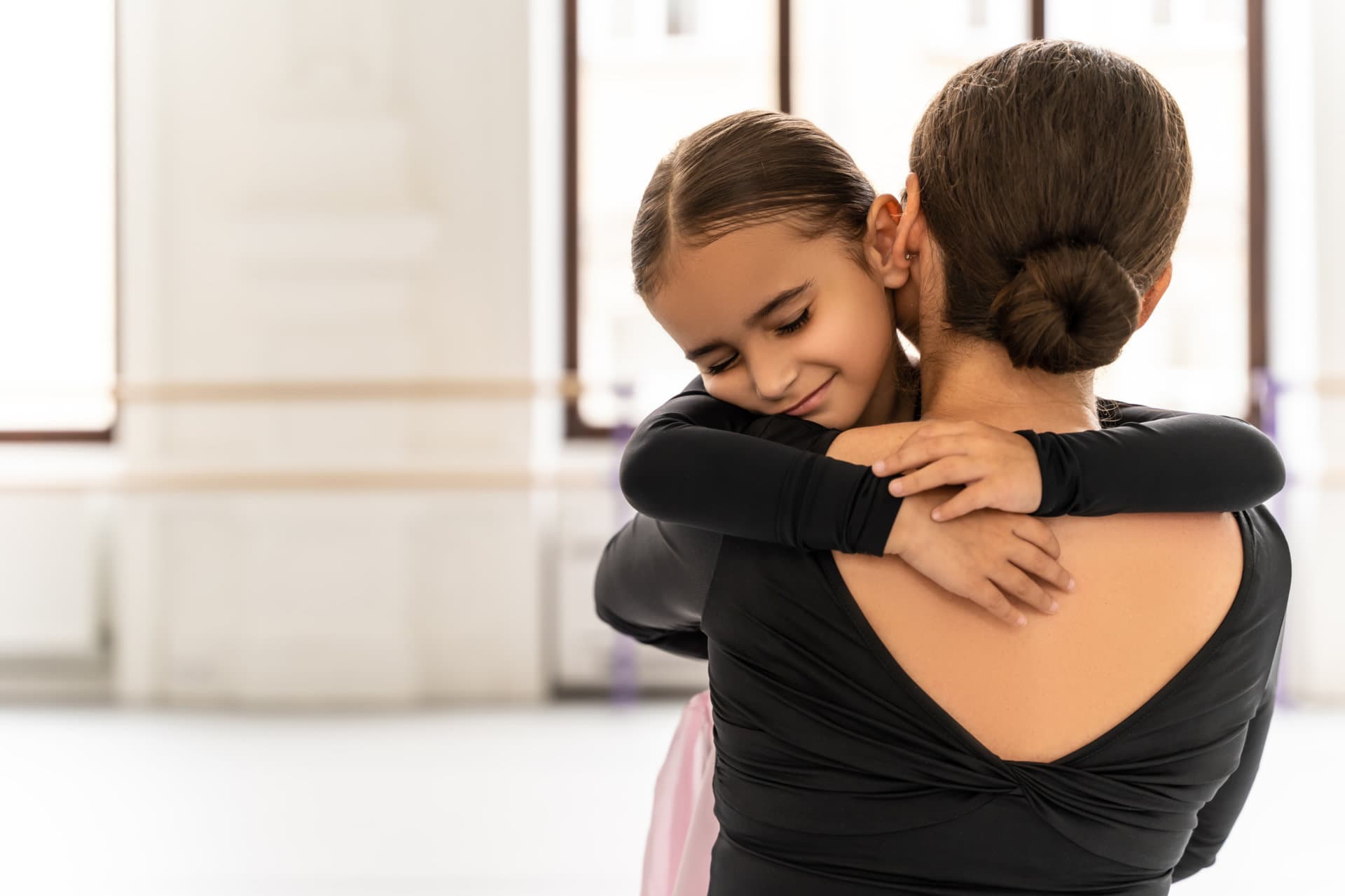 A young dancer embracing an encouraging teacher after class