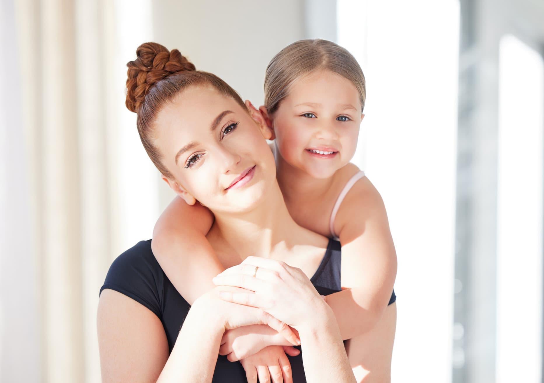 A young dancer smiling while embracing a supportive adult